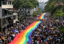 ¿Podemos marchar juntos quienes pensamos diferente? Multitud participa en la Marcha del Orgullo en Medellín portando una gran bandera arcoíris mientras una editorial reflexiona sobre diversidad, pluralismo y libertad de conciencia.