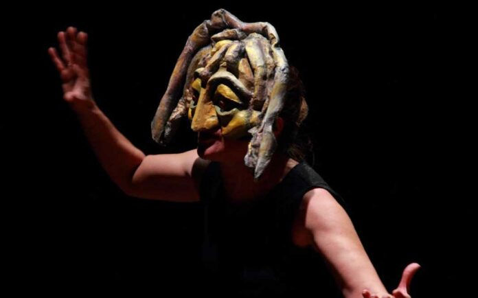 Artista con máscara durante una puesta en escena teatral en Medellín.