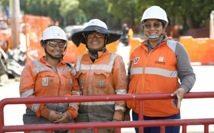 Tres mujeres trabajadoras con casco y elementos de seguridad en una obra de infraestructura en Medellín.