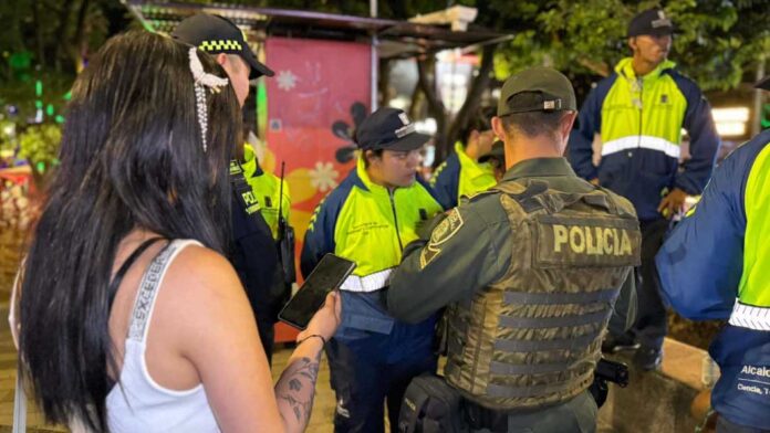 Policías y personal de la Alcaldía junto a una ciudadana durante una intervención nocturna en el Parque Lleras.